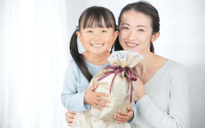 プレゼントを持つ笑顔の女児と女性