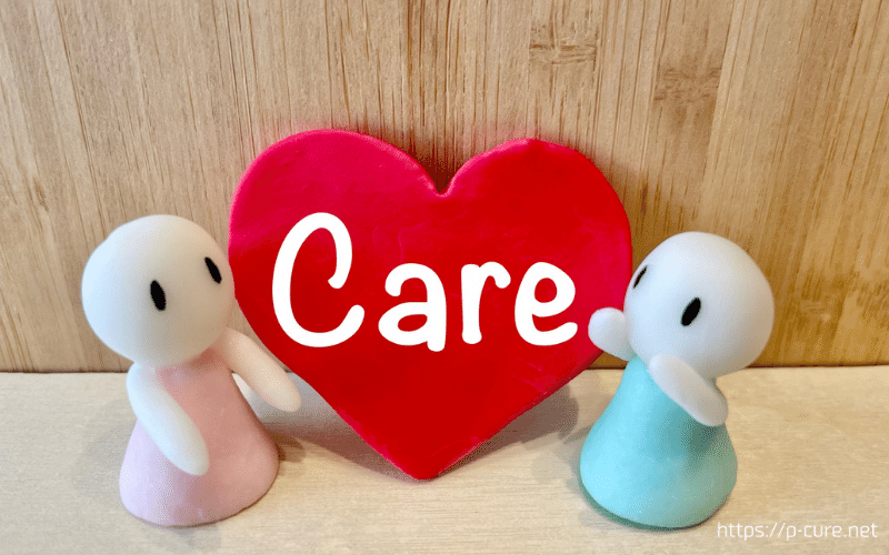 「care」と書かれた赤いハートと両側で支える2体の人形