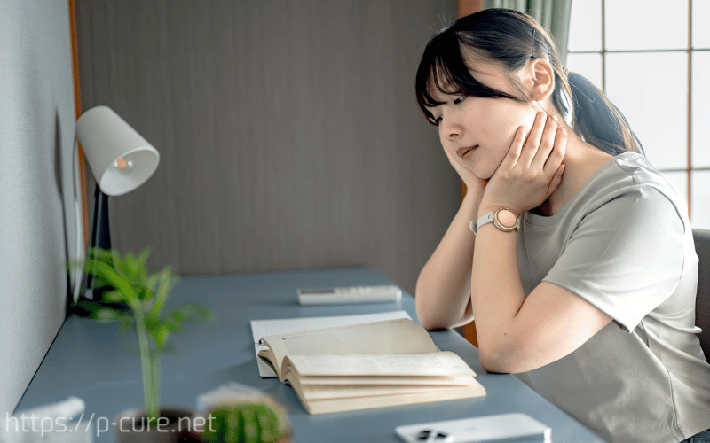 机に座って勉強しようとするけど集中できない女性